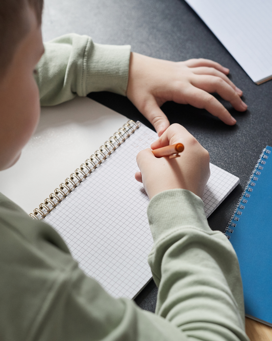 child writing in notebook
