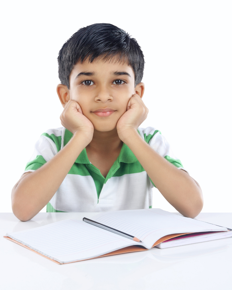 boy sitting with book and pencil